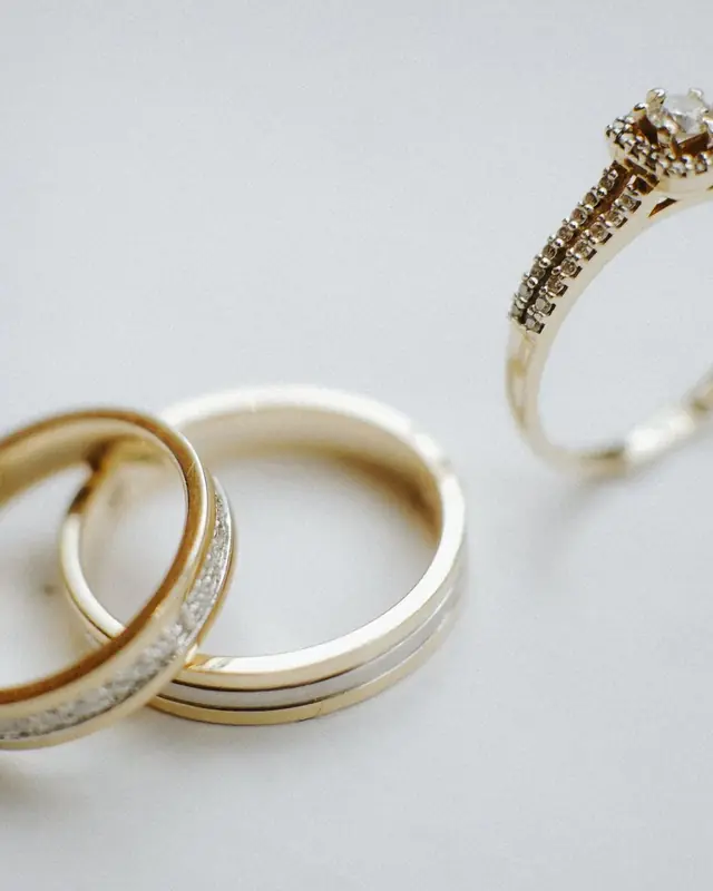 Gold bands and a small stone ring on a pale surface