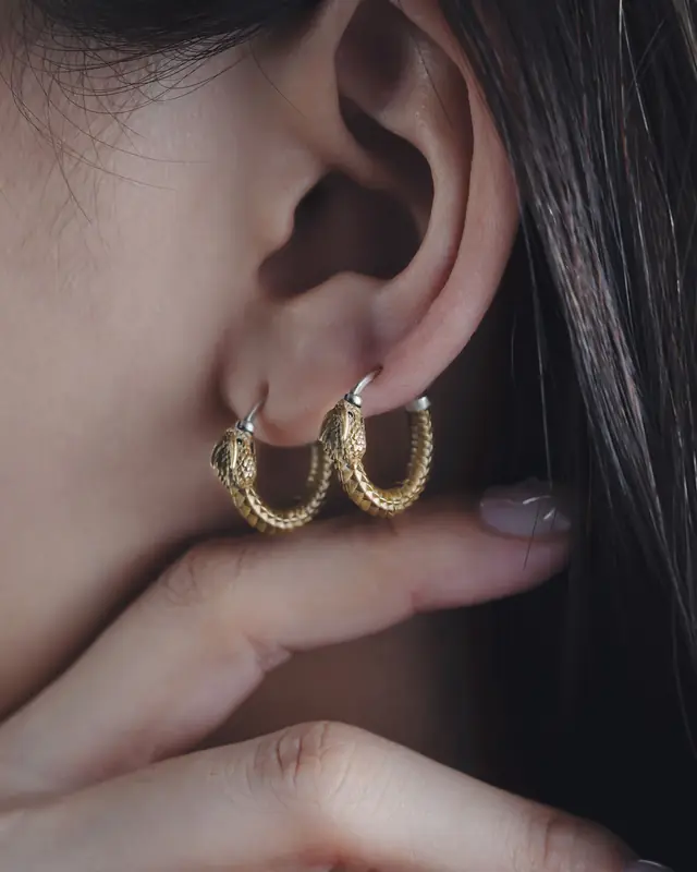 Gold hoop earrings worn on an ear