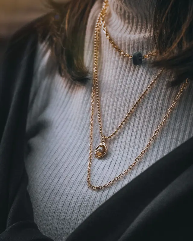 Layered gold chain necklaces over a ribbed knit