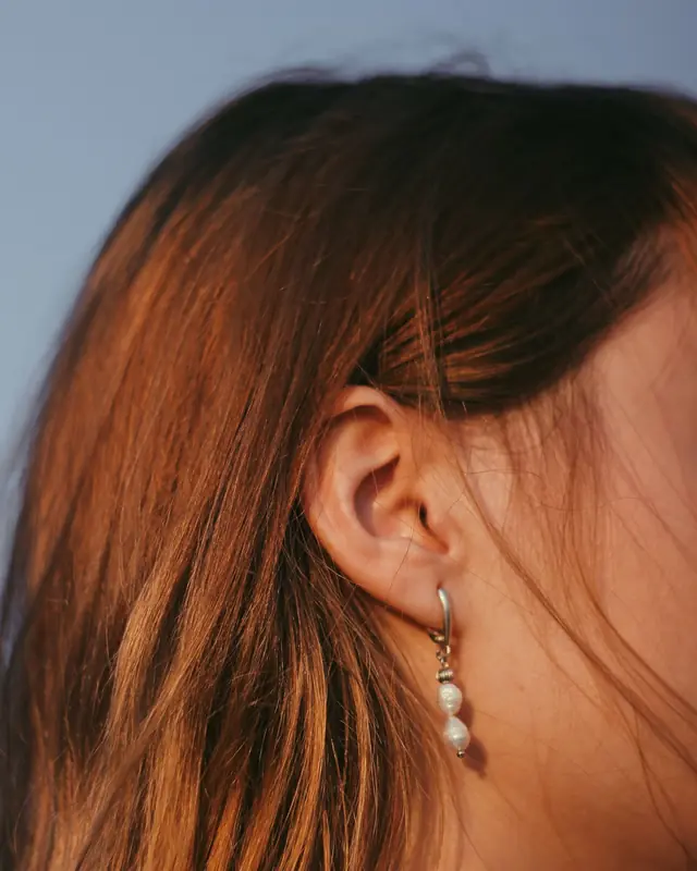 Pearl drop earring on a woman with auburn hair