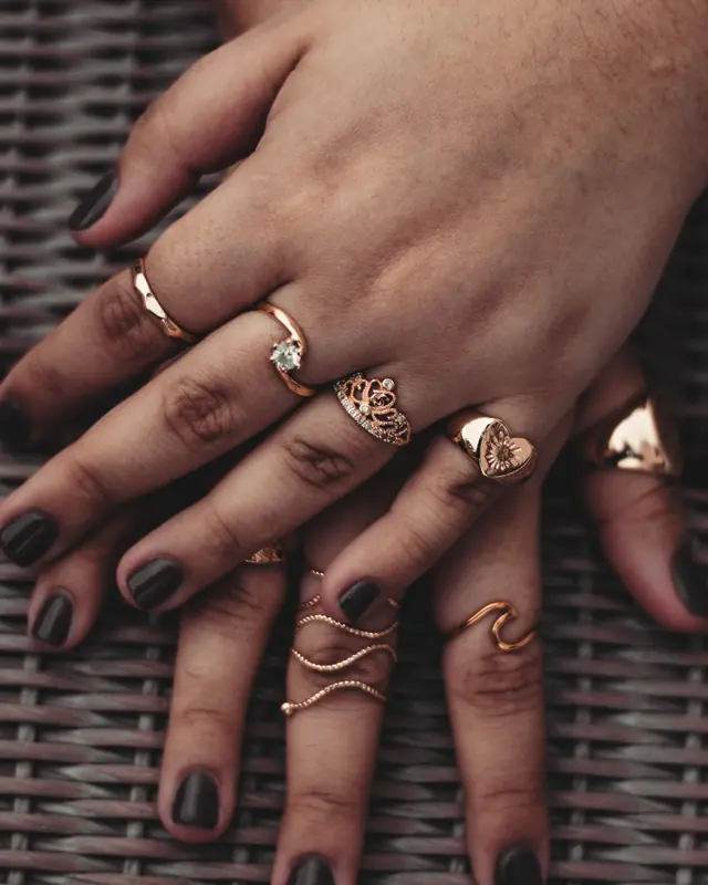 A hand wearing several slim gold rings