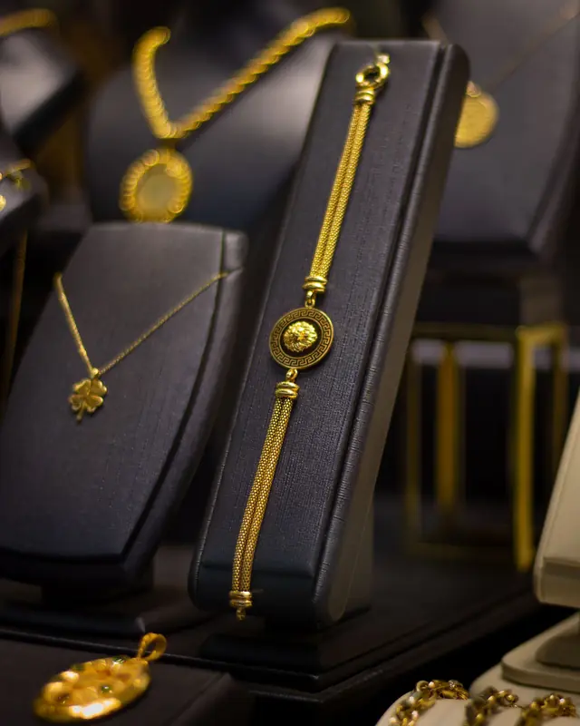 Gold bar bracelet and pendants on black display stands